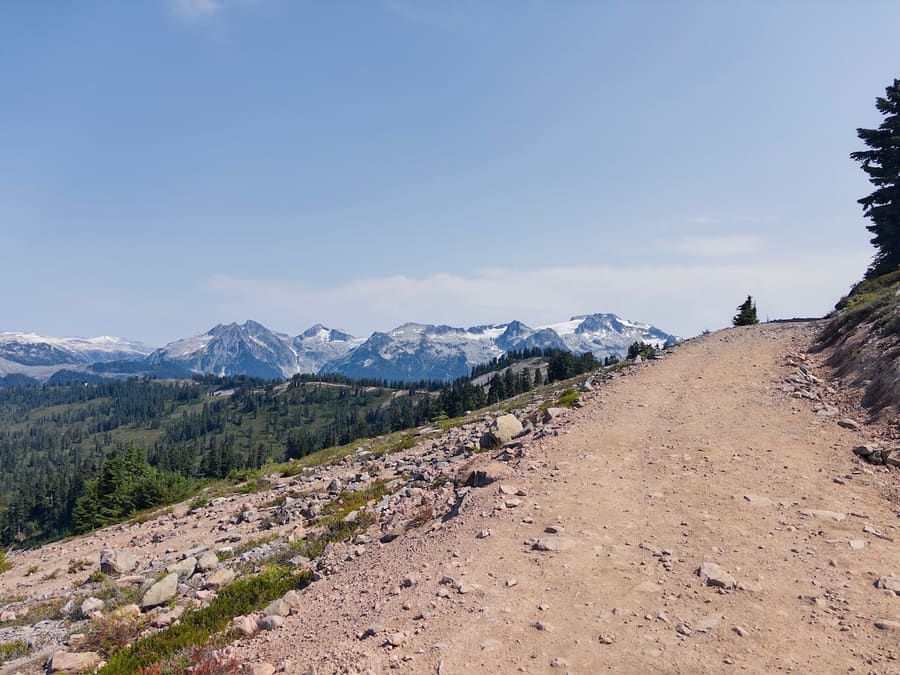 Rocky alpine trail facing a snow-capped mountain range