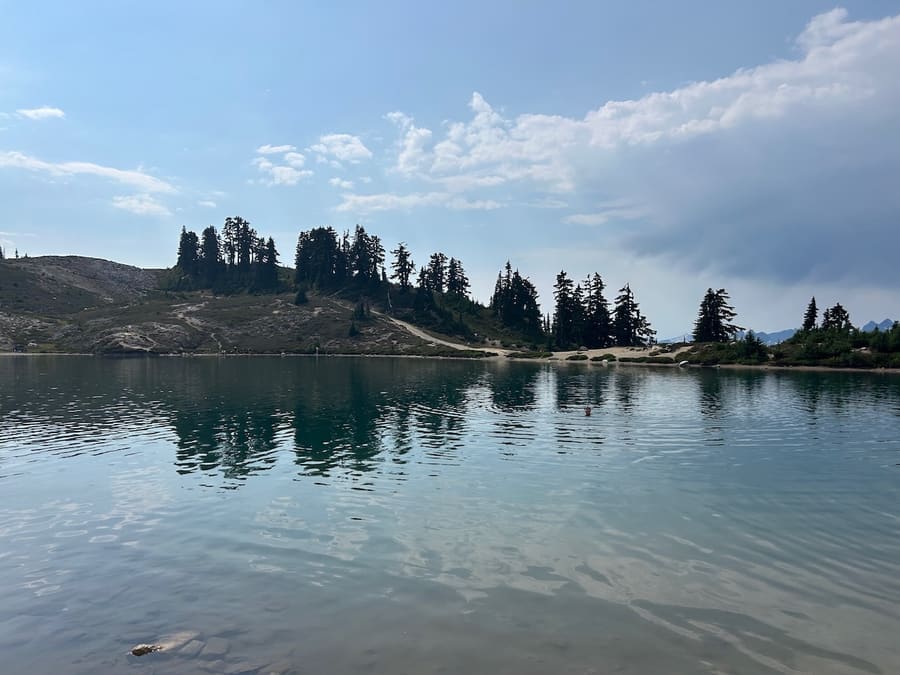 Calm alpine lake reflecting trees in Garibaldi Provincial Park