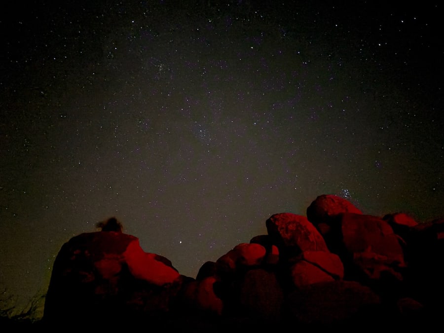 Red-lit boulders beneath the stars in Joshua Tree