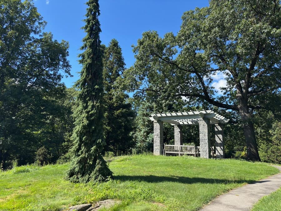Stone pergola and bench on a sunny garden hill