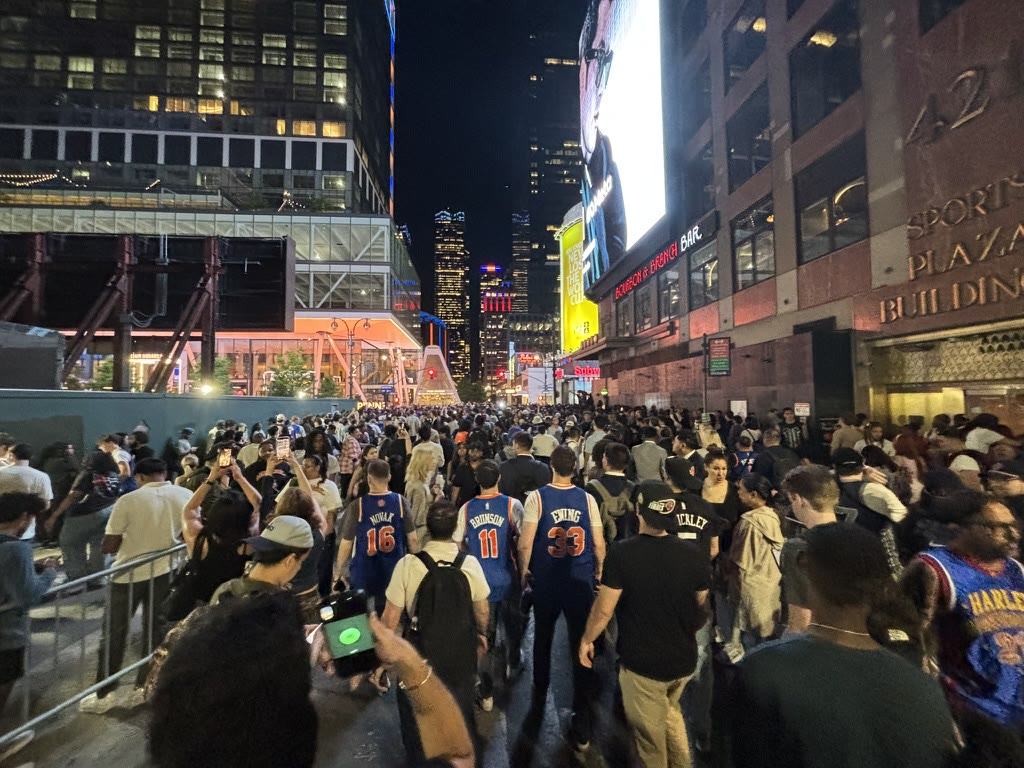 Knicks fans walking through the nighttime crowd outside Madison Square Garden