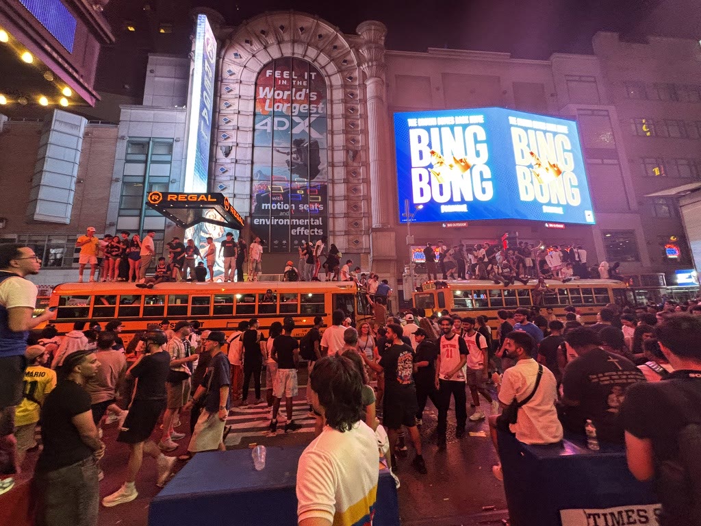 Knicks fans celebrating around buses beneath red lights in Midtown