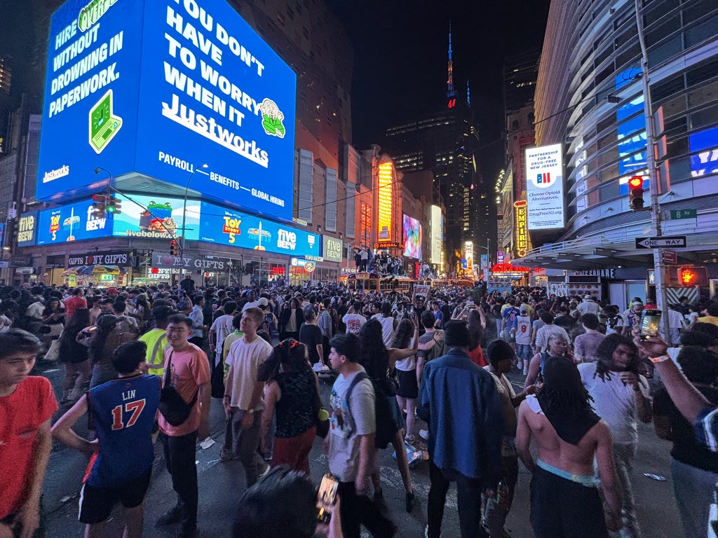 Wide view of a large Knicks crowd on Eighth Avenue at night