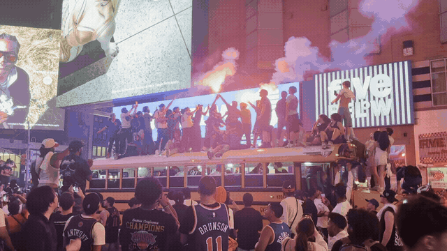 Knicks fans celebrating around a bus beneath smoke and city lights