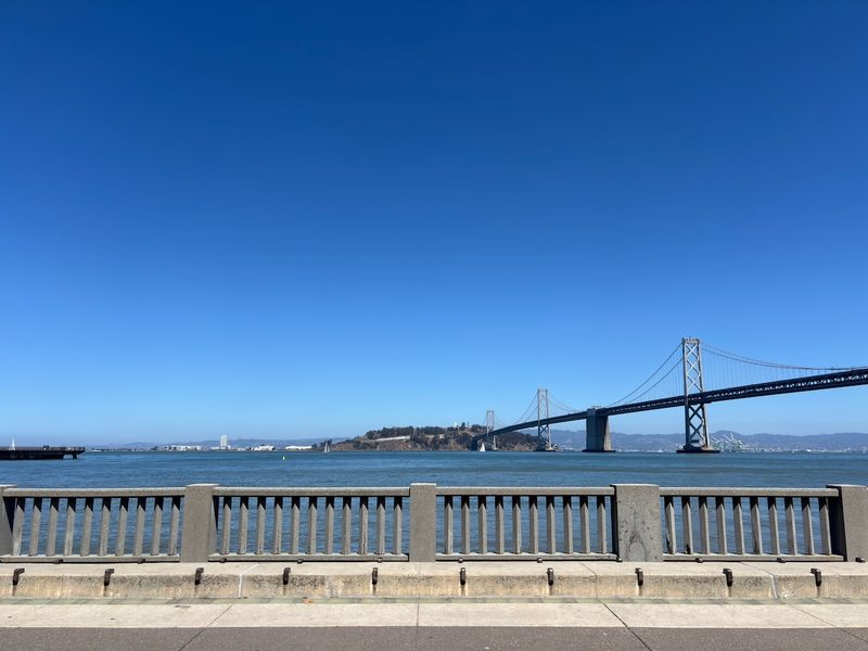 Bay Bridge across blue water from the Rincon Park waterfront