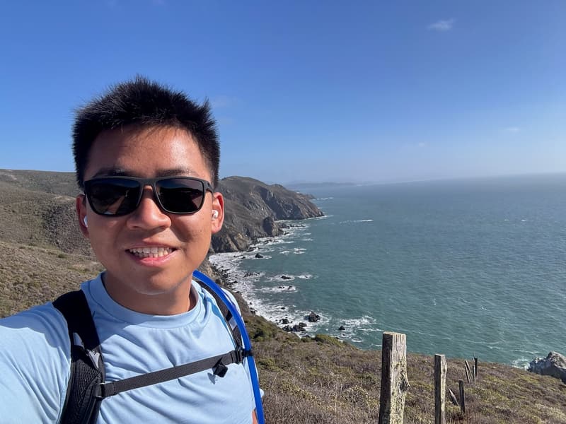 Alan wearing sunglasses and a backpack above the Marin coastline