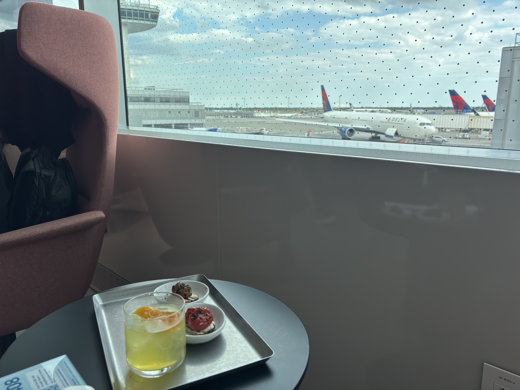 Lounge seat, small plates, and a drink overlooking the runway